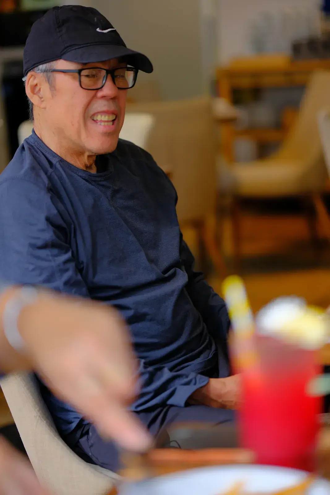 A smiling guest in a cap seated beside a red iced drink