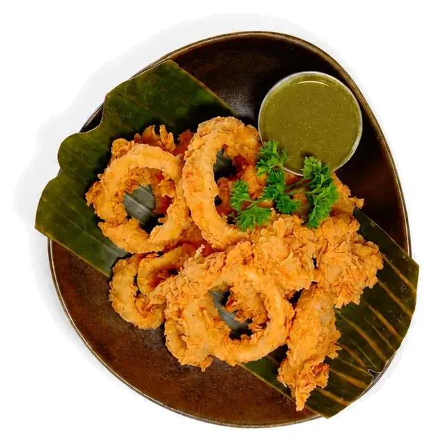 Fried calamari on a banana leaf with a green dipping sauce
